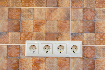 Electrical outlets on beige tiles with a vegetable pattern