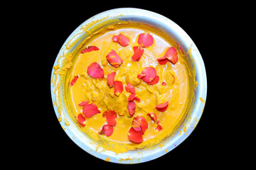 Haldi, in english called turmeric pest in bowl and rose petals on it and black background