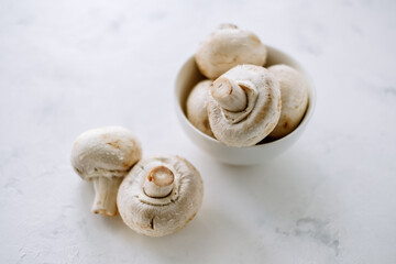 Fototapeta na wymiar Champignon mushrooms in a white bowl on the table close-up.
