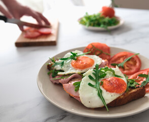 ham and egg on toast with sliced tomatoes and rocket leafs.