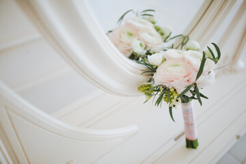 Floristics. A wedding bouquet of white flowers stands on a dressing table near the mirror
