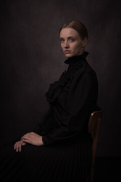 Studio portrait of sitting young woman in classic painterly renaissance style