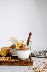 Granola and natural yogurt with slices of fruits and nuts in a glass cup, healthy breakfast.