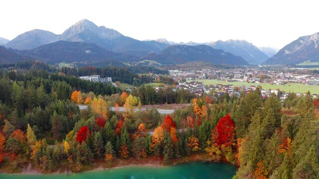 4k drone flight down footage (Ultra High Definition). Breathtaking morning scene of Urisee lake. Aerial view of Reutte town, Austria, Europe. Fantastic sunrise in Austrian Alps.