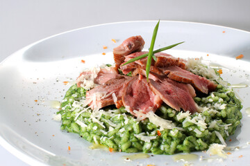 Ham and parmesan risotto with pesto on a white plate