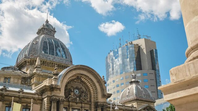 Time lapse of CEC Palace in Bucharest (Romanian: Palatul CEC, built in 1900) next to tall building with clouds reflected in its glass exterior. Popular downtown landmark for tourists visiting Romania.
