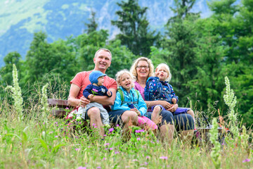Gutgelaunte Familie auf einer Bank inmitten einer Bergkräuterwiese