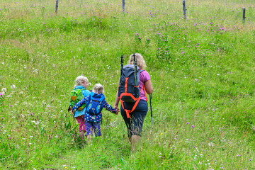 Wandernde Mutter mit Kindern auf einem Wiesenpfad