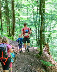 Junge Familie beim Wandern auf einem bergigen Waldpfad