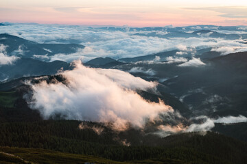 Fototapeta premium Amazing flowing morning fog in spring mountains glowing by sunrise. Beautiful sunrise on background. Landscape photography