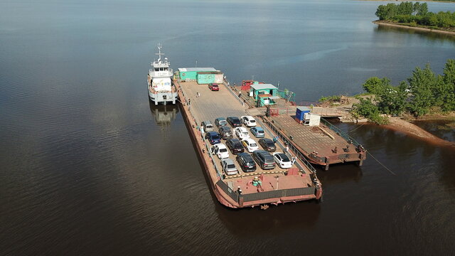 Aerial view of a typical Russian ferry boat transport cars and people. Aerial top view ship sails on the river Kama, Perm krai, Russia. Car and boat transportation on the sea, river, ocean and water.