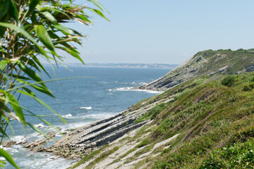 Corniche entre Ciboure et Hendaye au  pays Basque dans les Pyrénées Atlantique, roches couchées, transparence de l'eau, vagues et pêcheur © Ayma