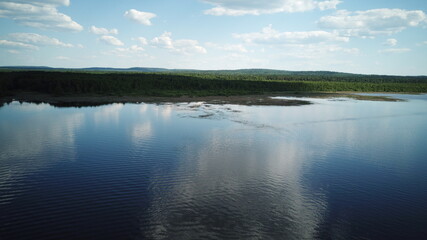 Aerial view of river Kama, Perm krai, Russia. Rural landscape from above, water waves, cloud reflection in water, trees on the coast, summer sun day. Copy space.