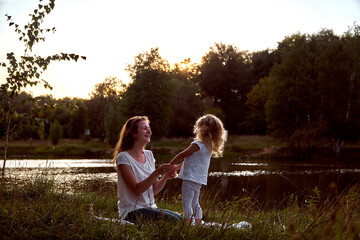 Fototapeta premium Mom and daughter on the street are looking at each other. Laughter and joy of a woman and a child. High quality photo