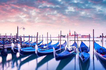 Colorful landscape with pink sunset sky on piazza San Marco in Venice. Row of gondolas parked on city pier. Church of San Giorgio Maggiore on background, Italy, Europe