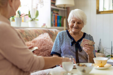 Senior woman and her adult daughter playing cards at home
