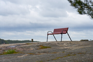 Wooden bench on rocks with clouds on a background.