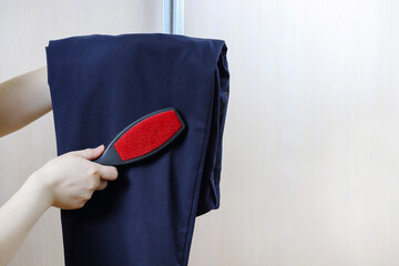 Cleaning the suit with a nap roller. Brush for clothes. Copy space - concept of caring for things,...