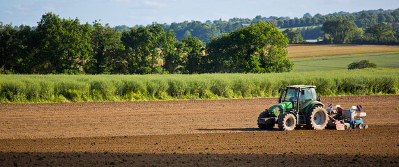 Agriculteur au volant de son tracteur labourant les champs de terre au printemps.