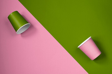 Pattern of paper cups located diagonally on a pink-green background. Ecological tableware. Minimalistic style. Top view.