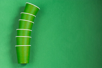 Paper cups on a green background. Ecological tableware. Minimalistic style. Top view. Copy space.