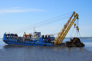 Russia, Saratov - june, 2020. industrial ship crane removed the old sunken ship from the river