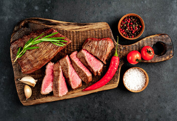 
Two grilled beef steaks with spices on a stone background