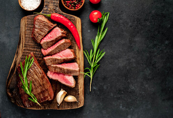
Two grilled beef steaks with spices on a stone background with copy space for your text.