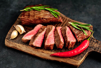 
Two grilled beef steaks with spices on a stone background