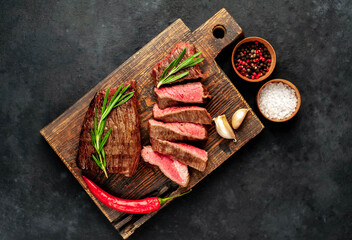 
Two grilled beef steaks with spices on a stone background