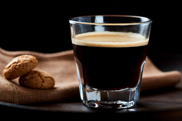 Coffee in glass cup with amaretti (Italian biscuits) on dark background. Close up. 