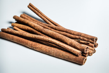 big heap of dry cinnamon sticks served on white table surface