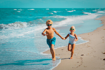 girl and boy running at beach, kids play with waves