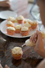 Kids baking and cupcakes decorating at home. View from behind.