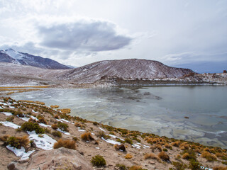 Fototapeta na wymiar Snowy andes mounatins and frozen lake near Salar De Uyuni, Bolivia