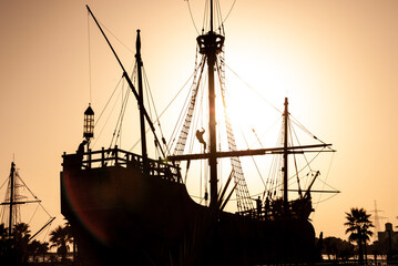 general shot, in silhouette, of an old caravel (ship), on a sunny day