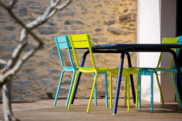 Salon de jardin, table et chaises sur une terrasse en bois.