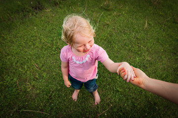 parent holding little girl hand in nature