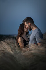 Young couple of man with beard and girl with long dark hair hugging and smiling between plants in...