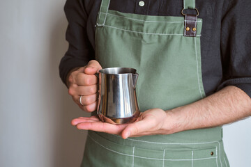 Man hold metal milk pitcher in his hands. Barista milk pitcher closeup. Metal milk jug. Milk...