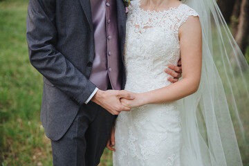 Wedding. Bride and groom. A guy in a suit and tie and a girl in a white wedding dress stand and hold hands