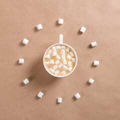A white cup of coffee with marshmallows on brown craft paper, marshmallows lie around in the form of a clock.