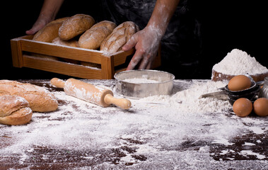 The table was full of bread flour And equipment for making bread And the chef is collecting the bread On a black background