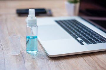 alcohol spray sanitizer and computer laptop on workplace at home office, protection coronavirus (Covid-19) infection. New Normal and personal hygiene concept