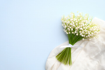 Bouquet of flowers lily of the valley and cloth on blue background with copy space. Mothers or...