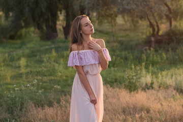 young woman walking in the park. Beautiful girl in a long dress at sunset. Summer and relaxation....