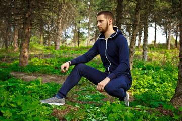 Handsome, young guy in a tracksuit plays sports in the park on the nature. Healthy lifestyle.
