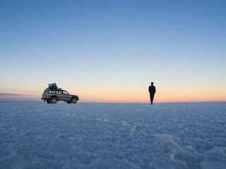 Man with his car at sunset at Salar de Uyuni in Bolivia