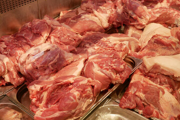 Fresh raw pork meat lies on the counter. A wide range of pork in a butcher's shop. An abundance of beautiful red raw pork meat.