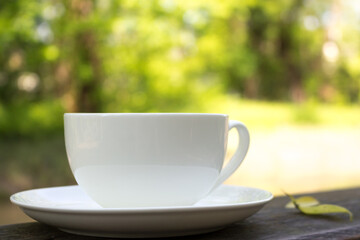 A white Cup on a wooden table on a Sunny summer day. An idyllic picture of the beginning of the day. Morning of a good day.